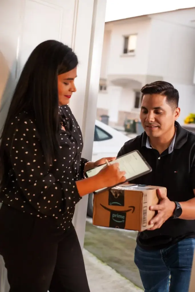 Woman signing on tablet for a package delivered by a courier at home.