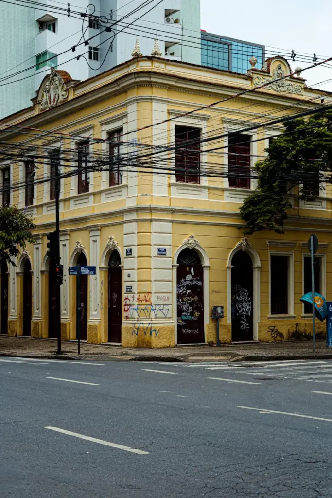 Corner view of a historic yellow colonial building with graffiti in Belo Horizonte, Brazil.
