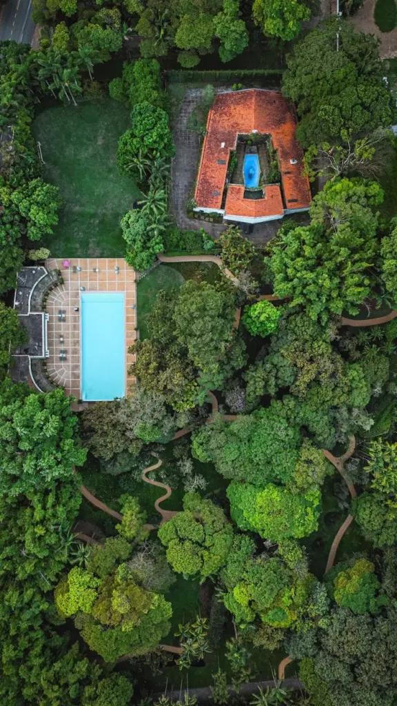 Aerial shot of a beautiful garden landscape with a villa and pool surrounded by greenery.