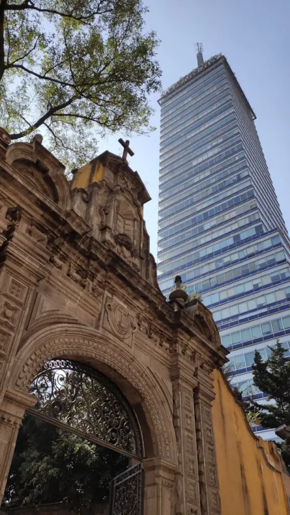 Juxtaposition of historic church entrance and modern skyscraper in Ciudad de México, showcasing architectural contrast.