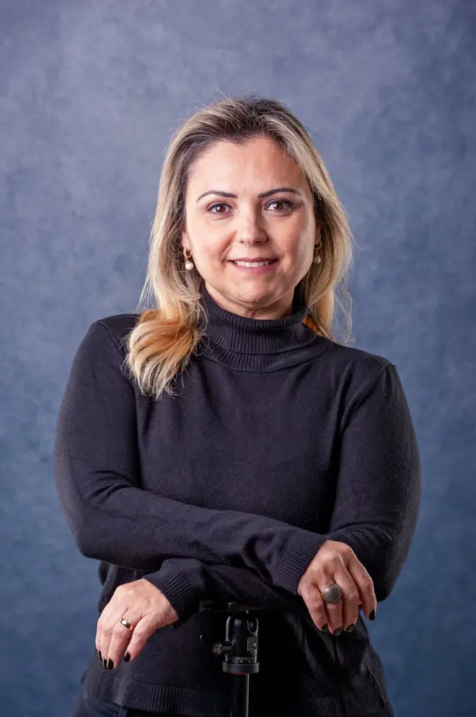 Portrait of a smiling woman in black sweater against a gray background.