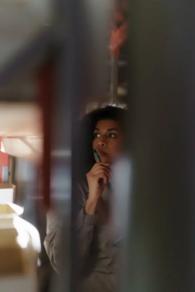 A thoughtful woman holding a pen, captured in soft focus with a warm, introspective mood.