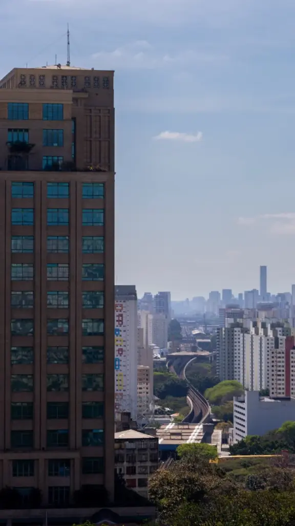 Aerial view of São Paulo skyline with prominent skyscraper and metro line in Brazil.