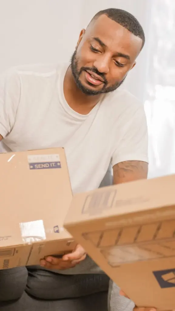 Bearded man holding and sorting packages at home, ideal for delivery or logistics themes.