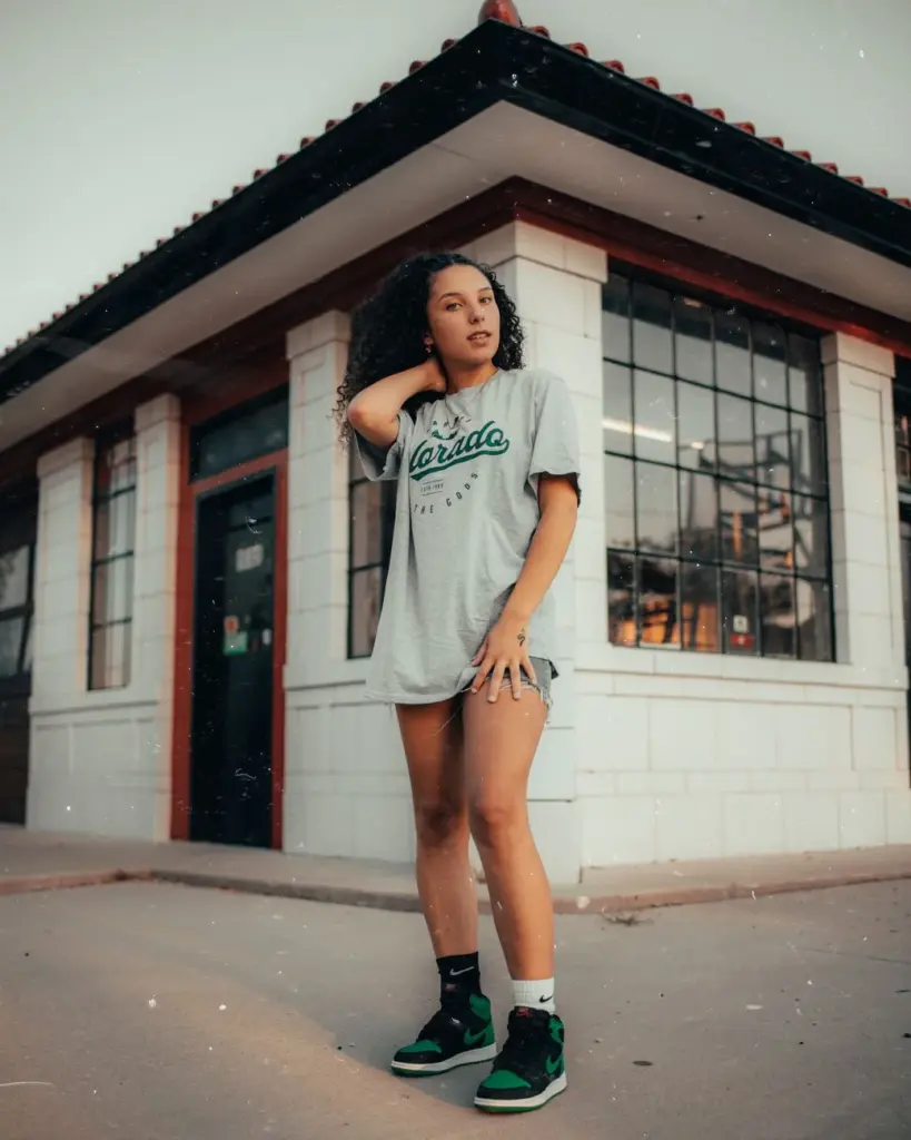 Stylish woman in a gray shirt poses confidently outside a building, showcasing casual fashion.