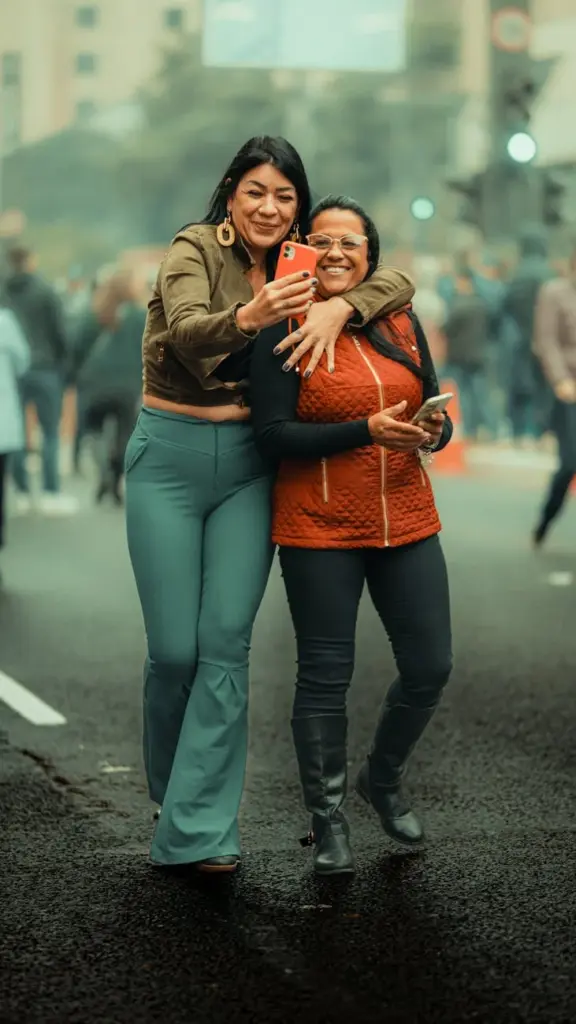 Two women happily taking a selfie in a bustling city street, showcasing friendship and joy.