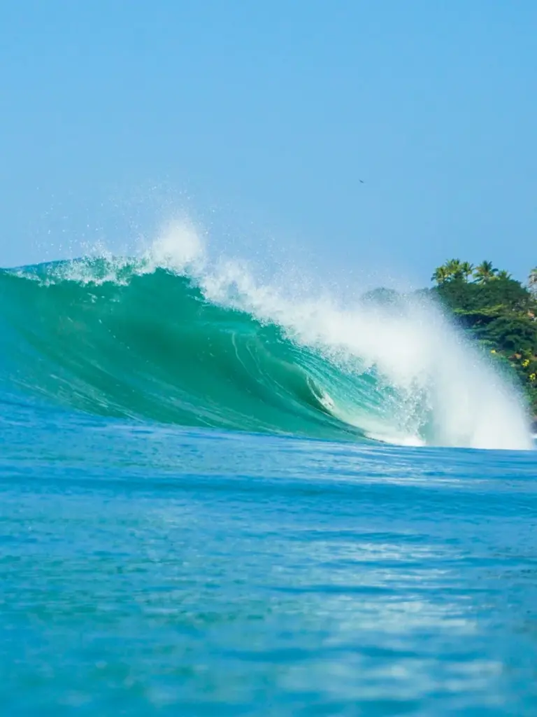 Dynamic view of a powerful wave crashing in Ubatuba, Brazil's clear blue sea.