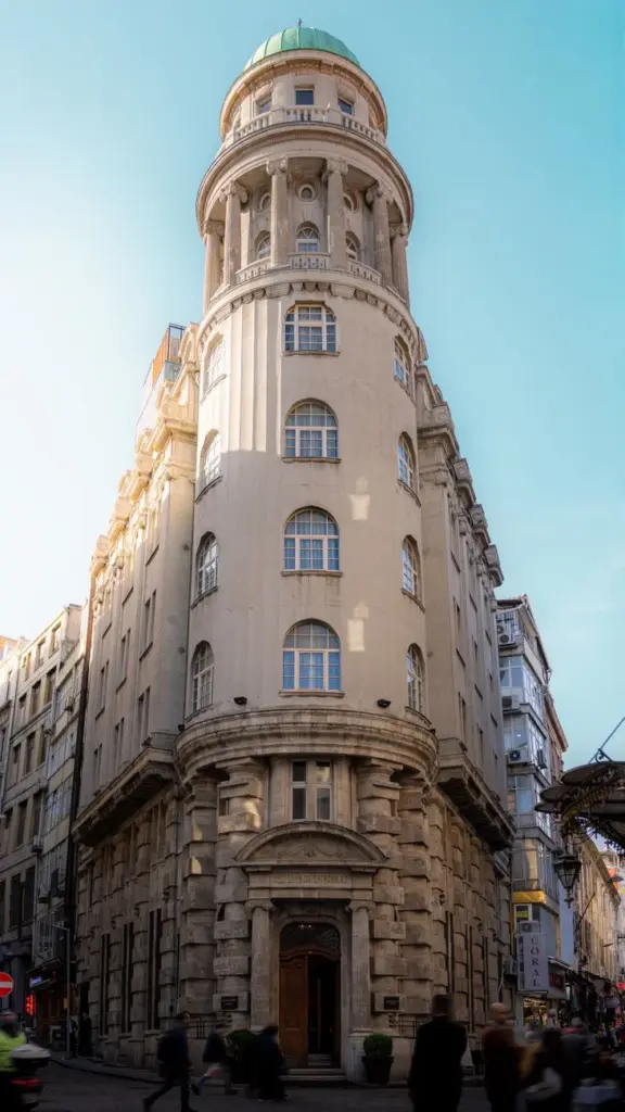 A classic cylindrical building with a green dome against a clear blue sky, showcasing early 20th-century architecture.