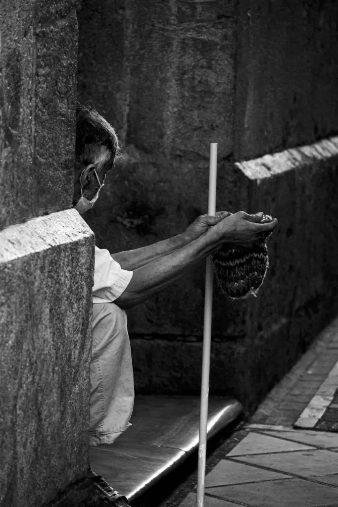 A black and white portrait of a solitary beggar with a hat in Cuenca, Ecuador.