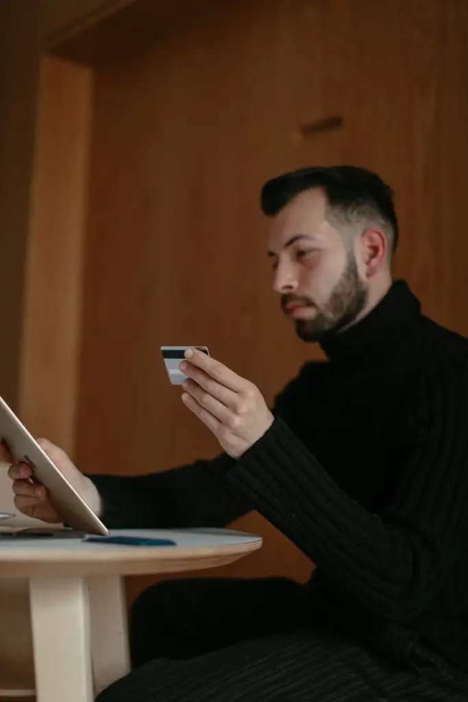 Bearded adult man using a tablet and credit card for online shopping at home.