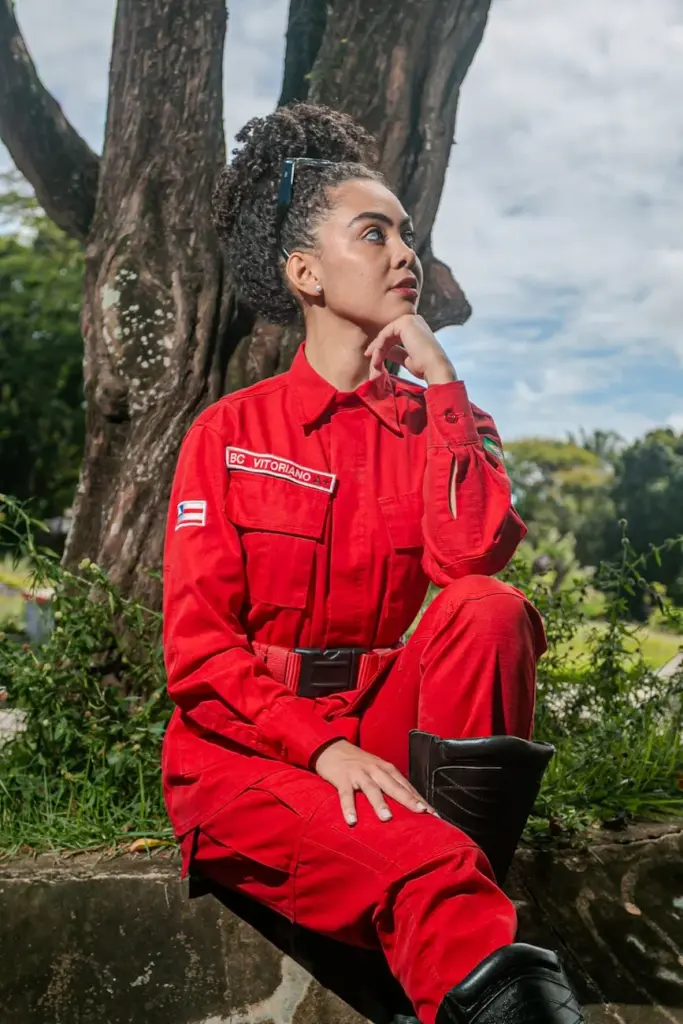 Firefighter in red uniform sitting outdoors, showcasing strength and determination.
