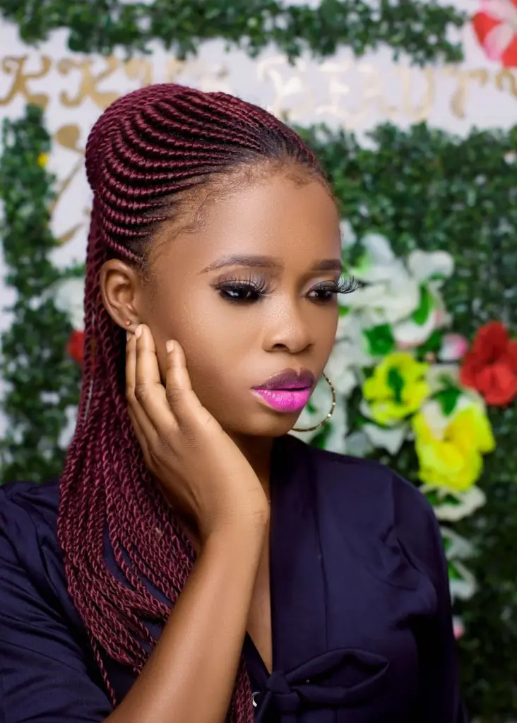 Stunning portrait of a woman with braided hair and vibrant makeup, showcasing timeless beauty.