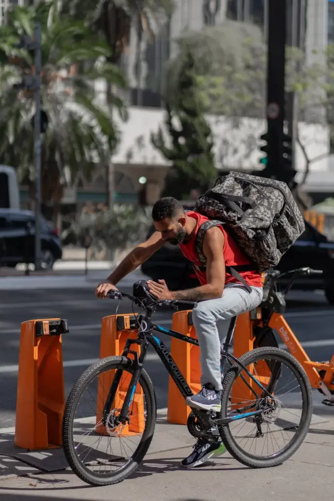 Cyclist wearing camouflage backpack using bike parking station in urban area, daytime shot.