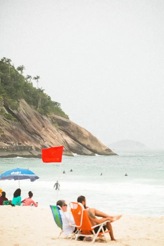 Visitors relax on a tropical beach with lush greenery and ocean waves, perfect for a serene getaway.