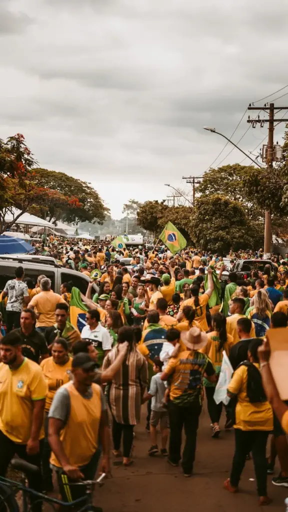 A large crowd participates in a peaceful demonstration, waving Brazilian flags on a busy street.