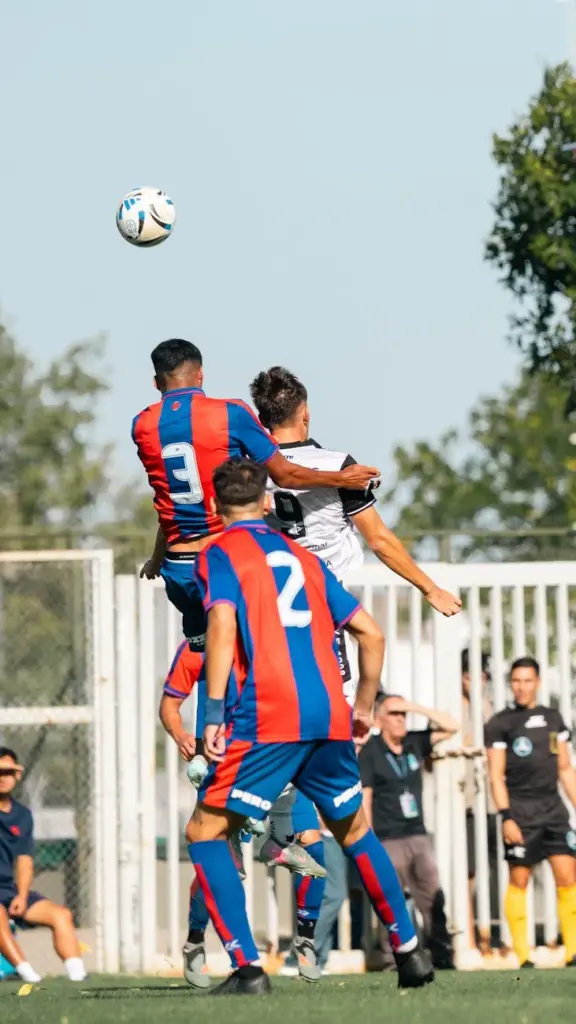 Players in an action-packed soccer match leap to head the ball, showcasing competitive sportsmanship.