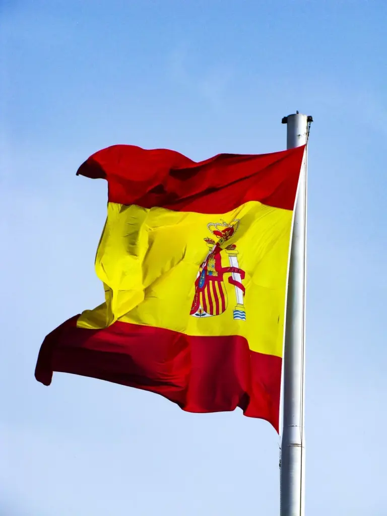 Spanish national flag fluttering in the wind against a bright blue sky, showcasing national pride.