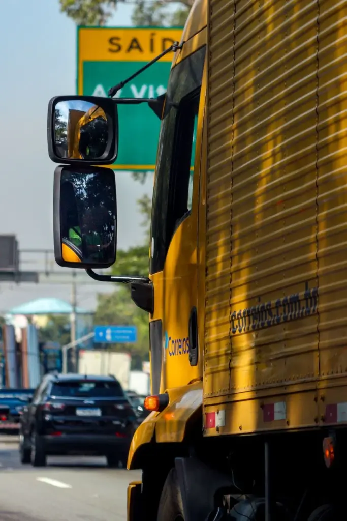 Yellow delivery truck navigating a busy highway in São Paulo, Brazil.