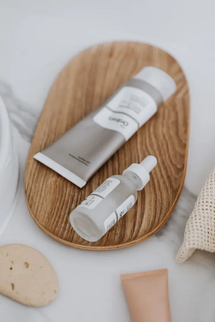 Minimalist display of skincare products including a serum and cream on a wooden tray, promoting eco-friendly beauty.