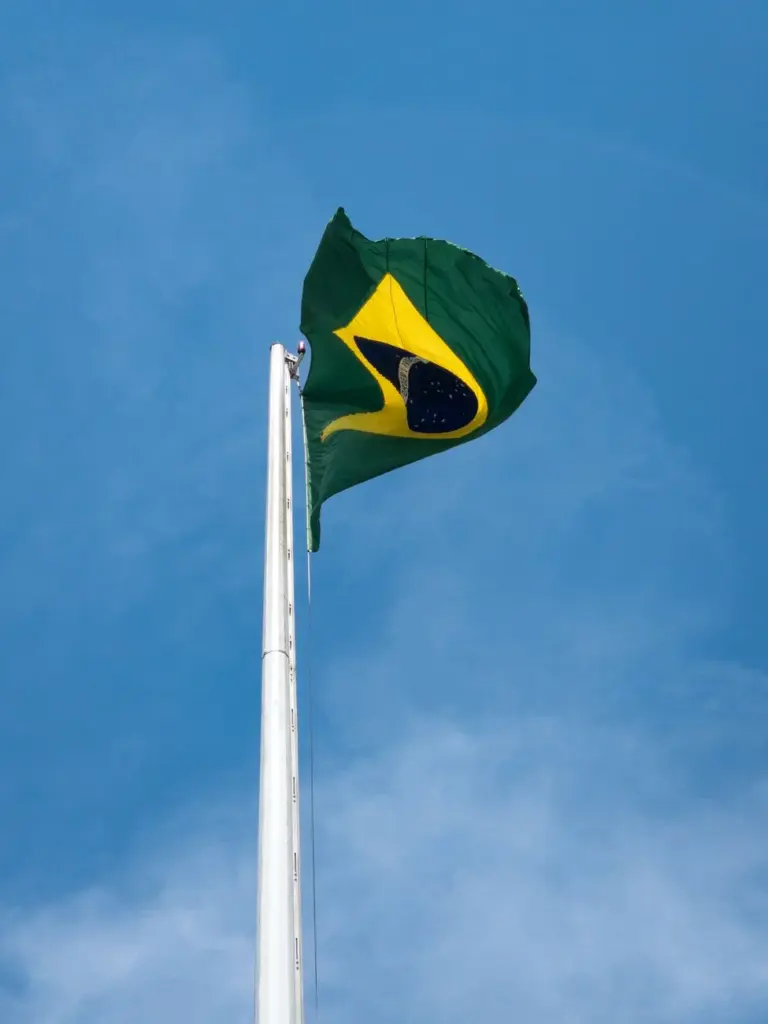 A vibrant Brazilian flag waving prominently against a clear blue sky, symbolizing national pride.