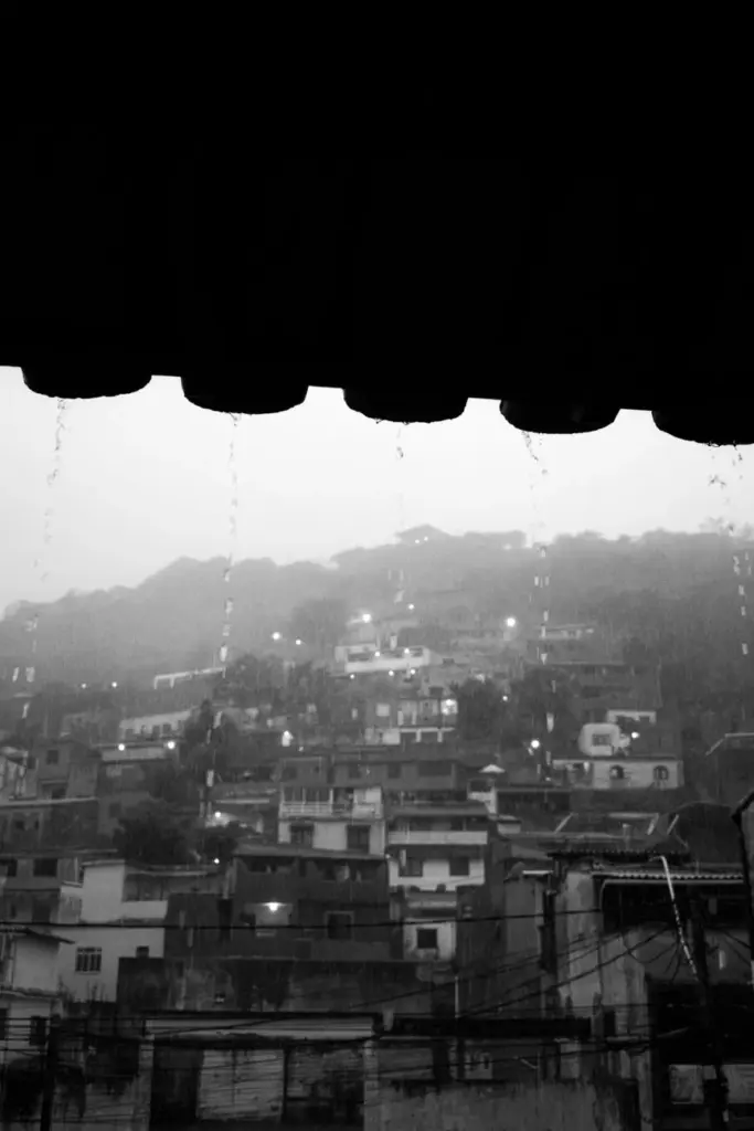 Dramatic black and white photo of favela rooftops in rainy Rio de Janeiro.