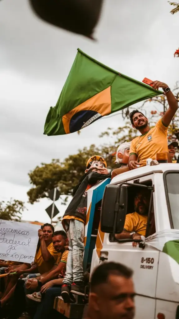 Group of Brazilian protesters waving national flag from a truck during a demonstration.