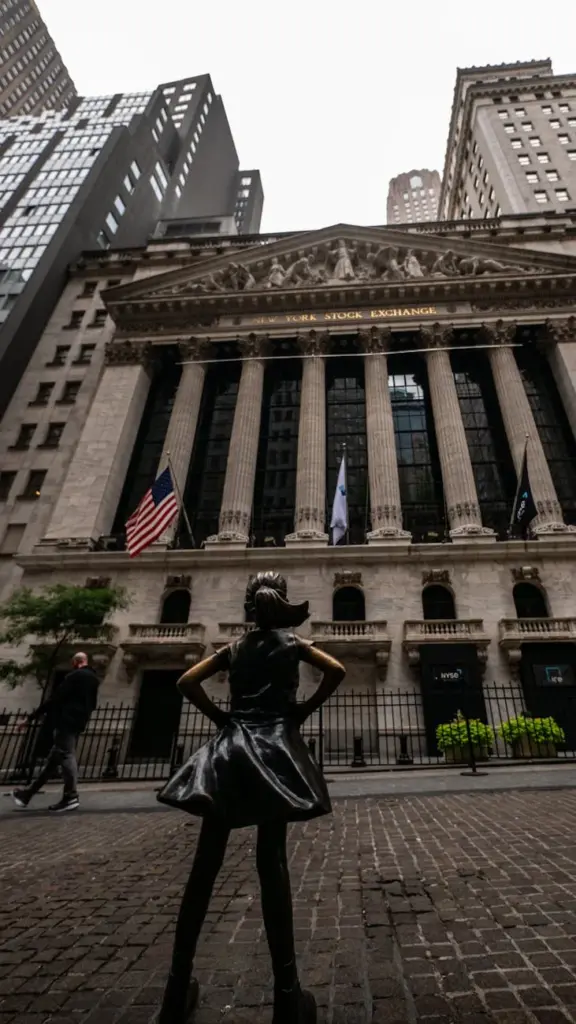 The Fearless Girl statue bravely stands facing the iconic New York Stock Exchange building.