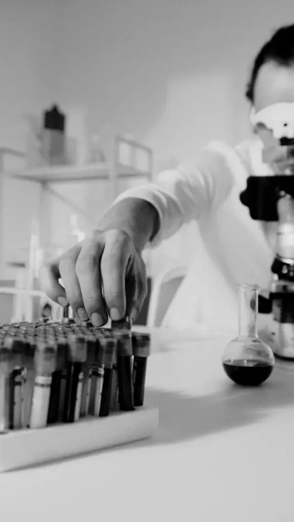 Focused scientist working with microscope and test samples in lab.