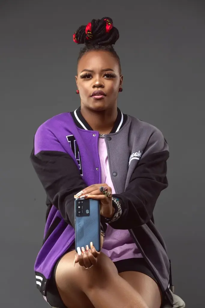 Young African woman with fashion makeup and smartphone in studio portrait.