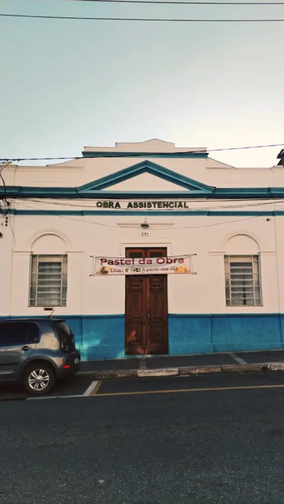 Front view of a historic urban building with blue accents and a sign advertising a local event.