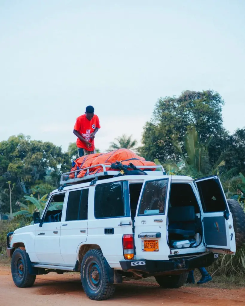 An adult loading equipment onto an SUV roof rack in Monrovia, Liberia scenery.