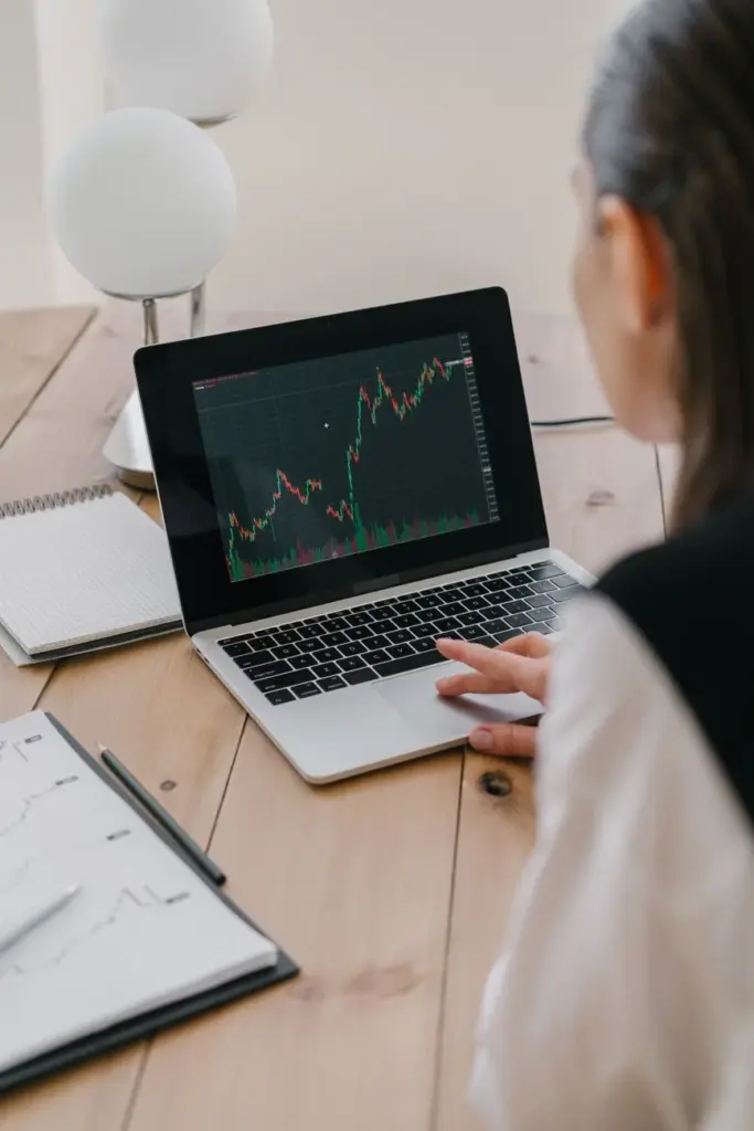 Individual using a laptop to review financial charts and analyze stock market trends.