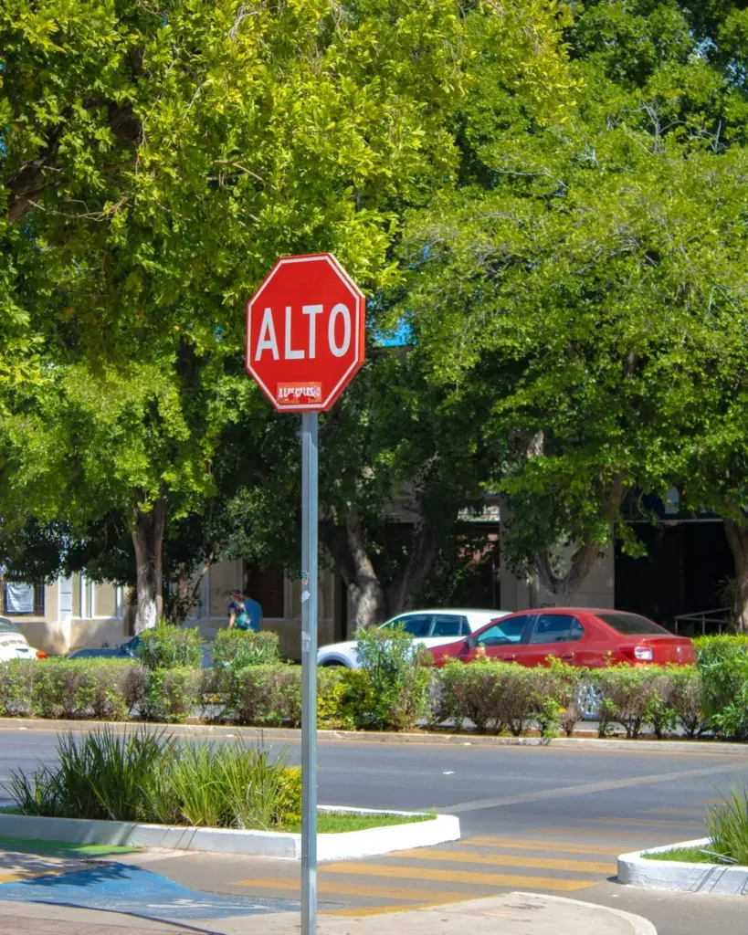 A stop sign labeled 'Alto' on a sunny street in Mérida, Yucatán, Mexico.