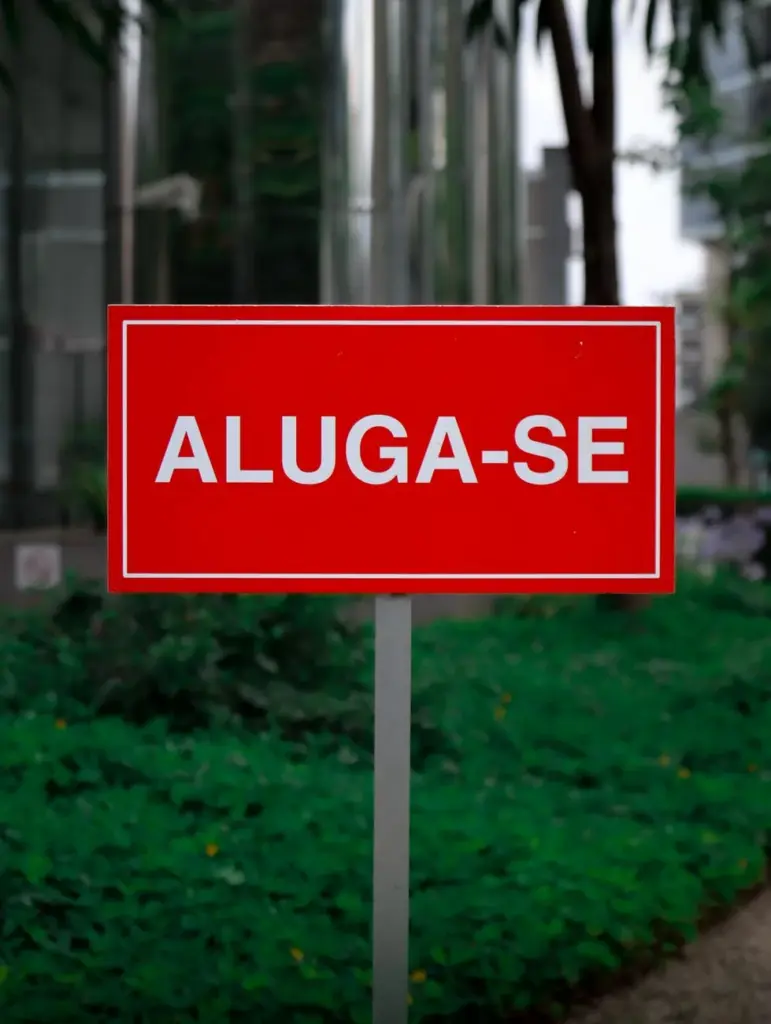 Red Aluga-Se sign outdoors with skyscrapers, symbolizing rental opportunities.