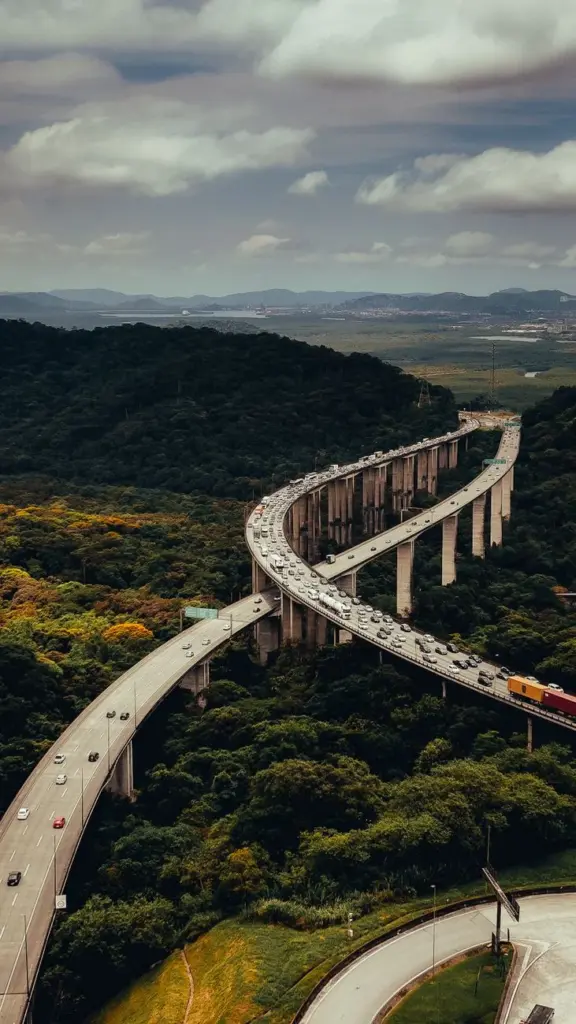 Aerial view of a highway winding through dense forest, showcasing nature and infrastructure.