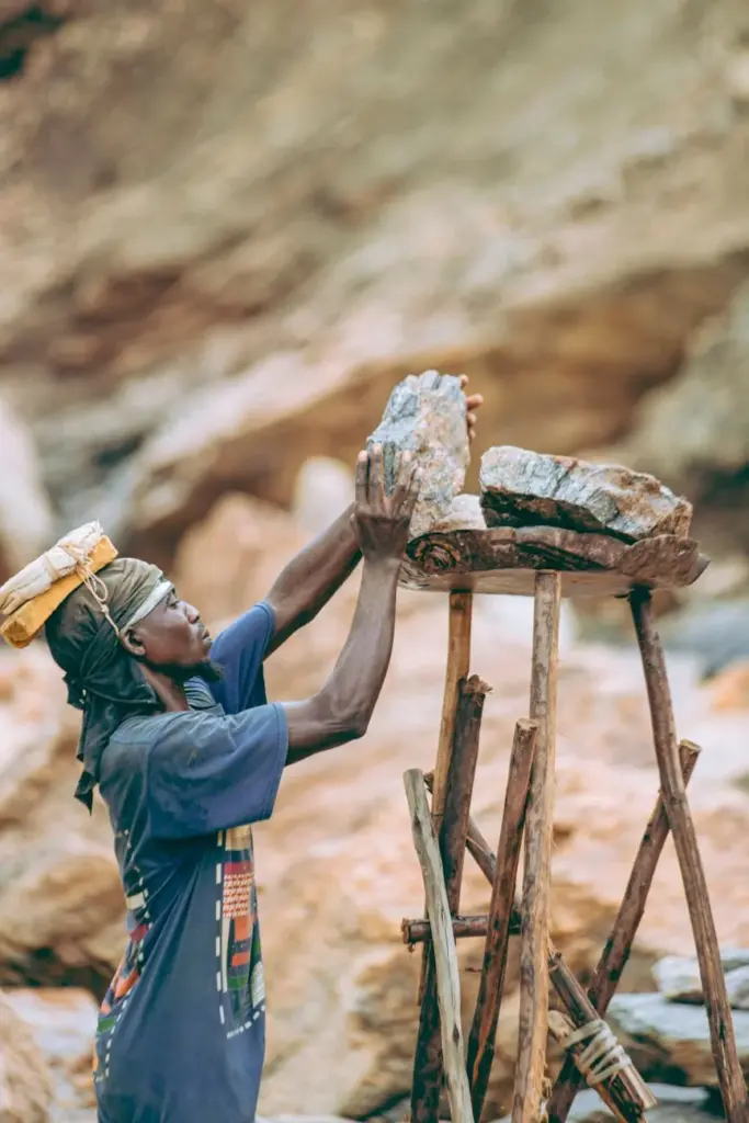 A dedicated artisan carefully balances large rocks in an outdoor setting, showcasing traditional skills.