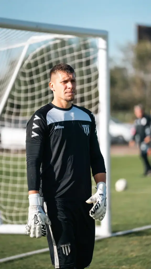 Goalkeeper in full gear standing on a soccer field during daytime practice session.
