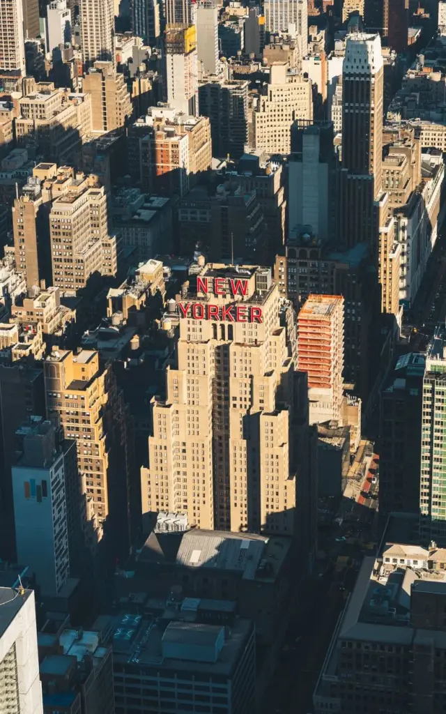 Aerial shot of the iconic New Yorker building amidst Manhattan's skyline in vibrant daylight.