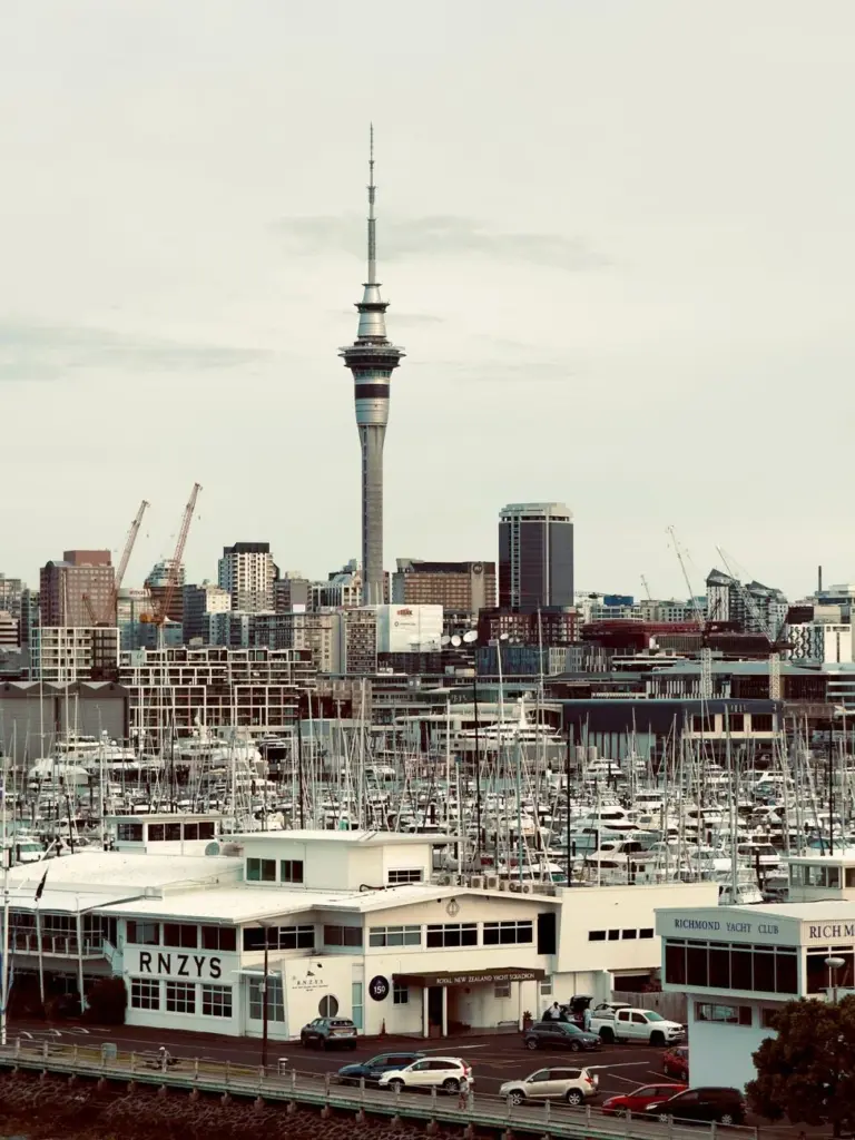A scenic view of Auckland's iconic Sky Tower with bustling harbor and cityscape.