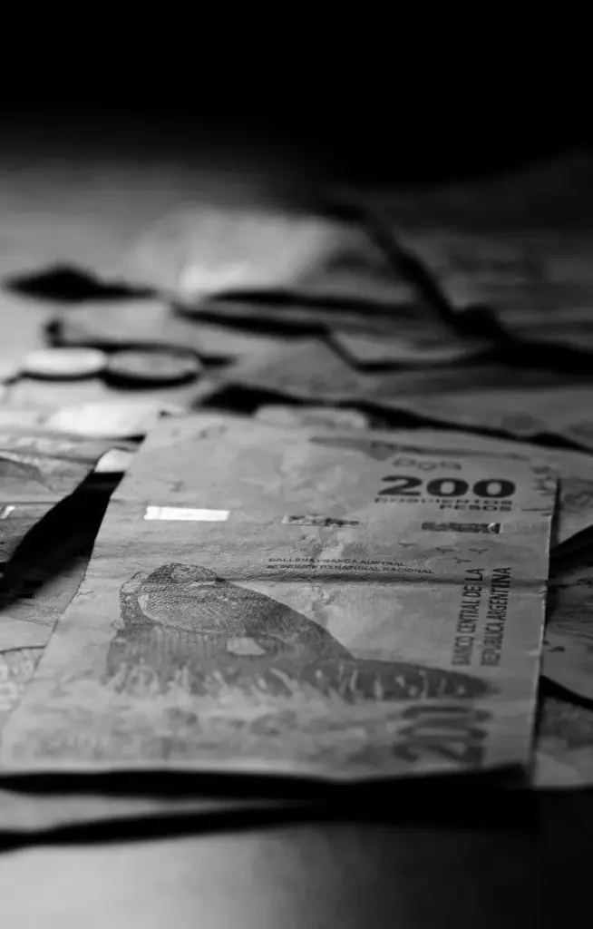 Black and white photo of Argentine peso banknotes and coins in Buenos Aires.
