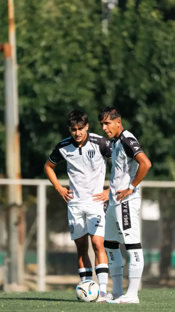 Two soccer players in white uniforms preparing for a free kick on a sunny day.