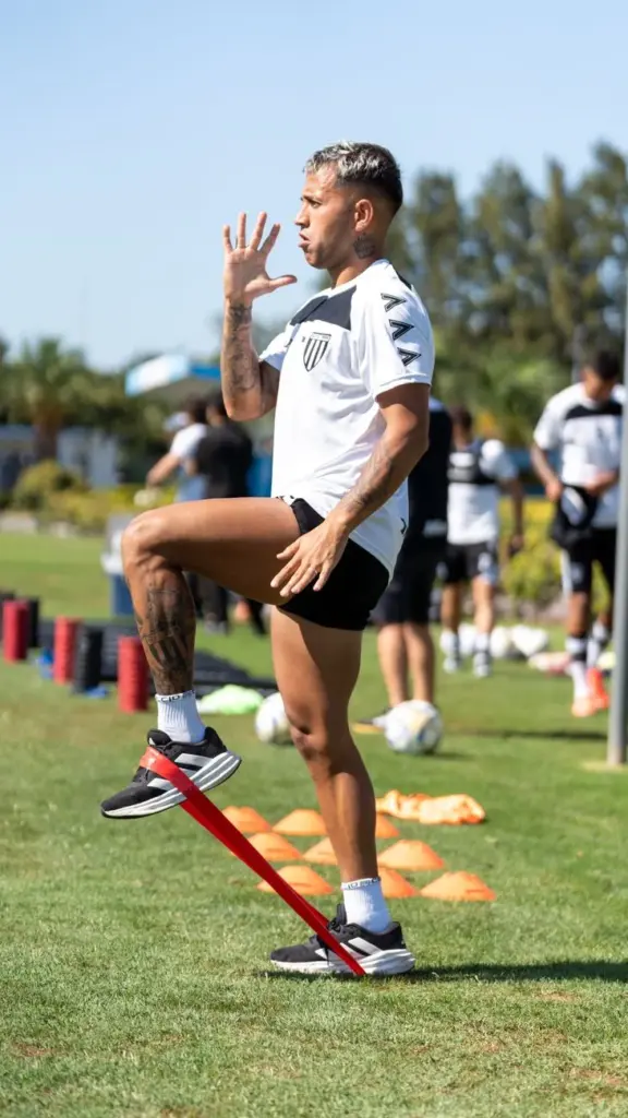 Soccer player exercising with resistance band during outdoor training session, demonstrating fitness and agility.