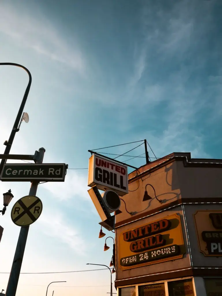 A nostalgic view of United Grill diner and Cermak Rd sign under a bright blue sky.