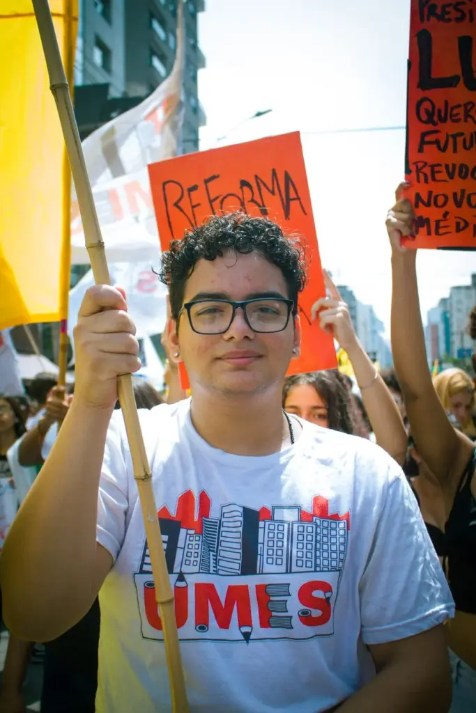 Group of young adults participating in a street protest holding banners and flags.