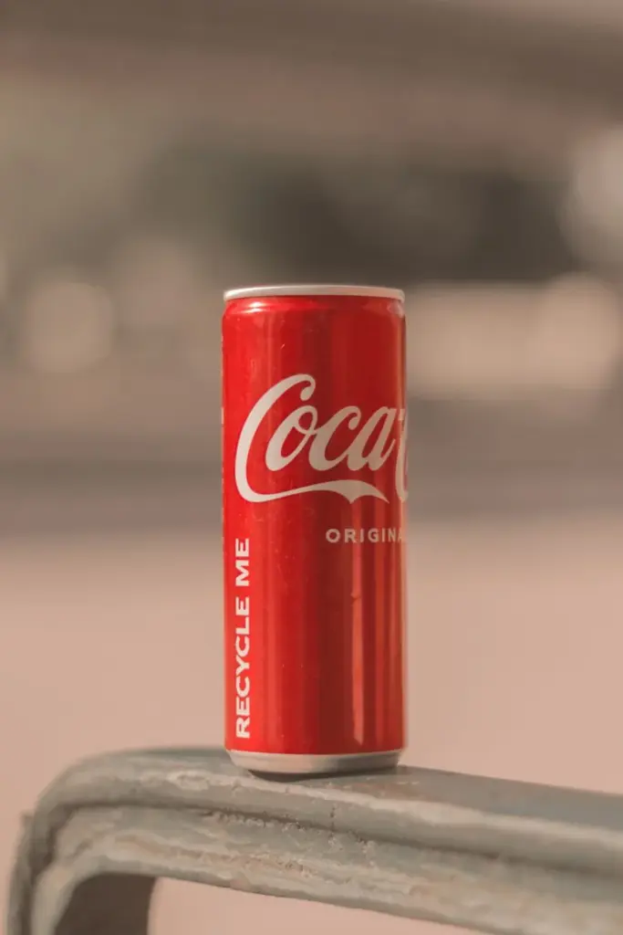 Close-up of a Coca-Cola can with a soft background, showcasing branding and recycling message.