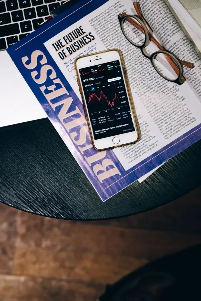 Smartphone displaying stock data on a magazine titled 'The Future of Business'.