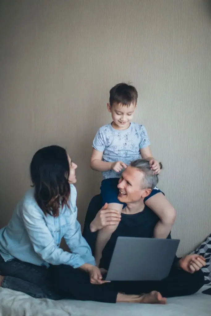 Family enjoying togetherness while working remotely at home on a laptop.