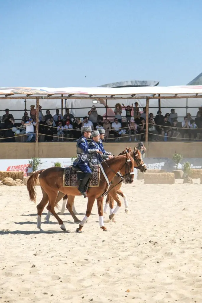 Performers on horseback displaying traditional costumes at an outdoor festival.