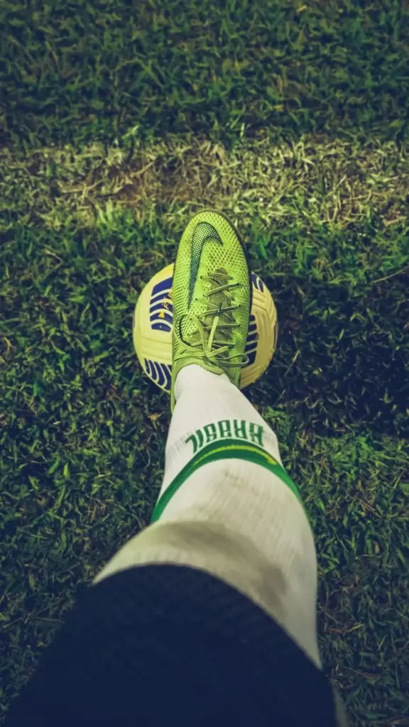 Action shot of a soccer shoe on a ball during a nighttime game, highlighting sports equipment.
