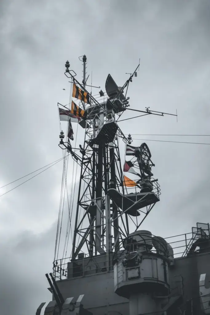 Dramatic view of a historic battleship's mast with signal flags in London.